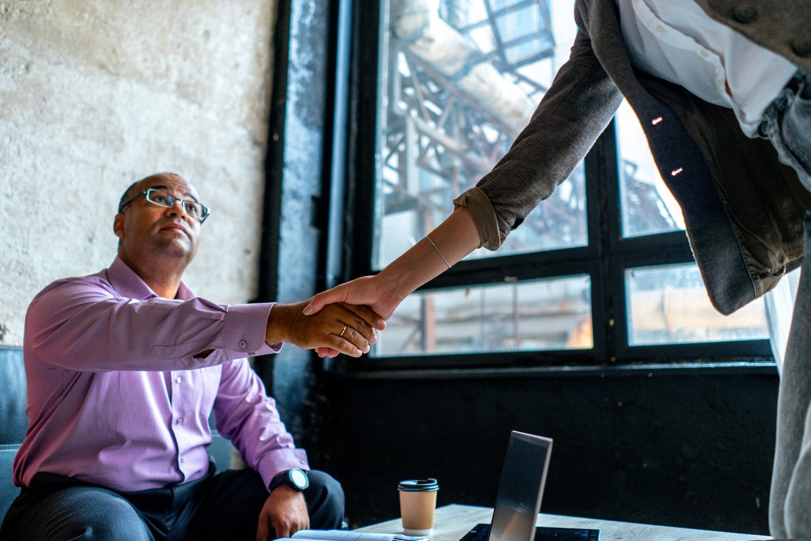 Professional handshake in an urban office setting, symbolizing agreement and networking.